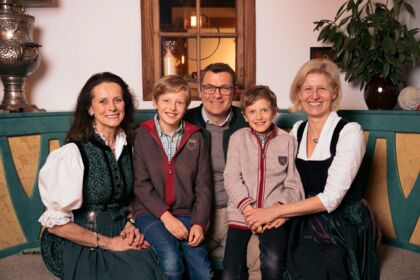 Eine lächelnde Familie in traditioneller Kleidung, gemütlich im Chalet-Karntner-Stil.