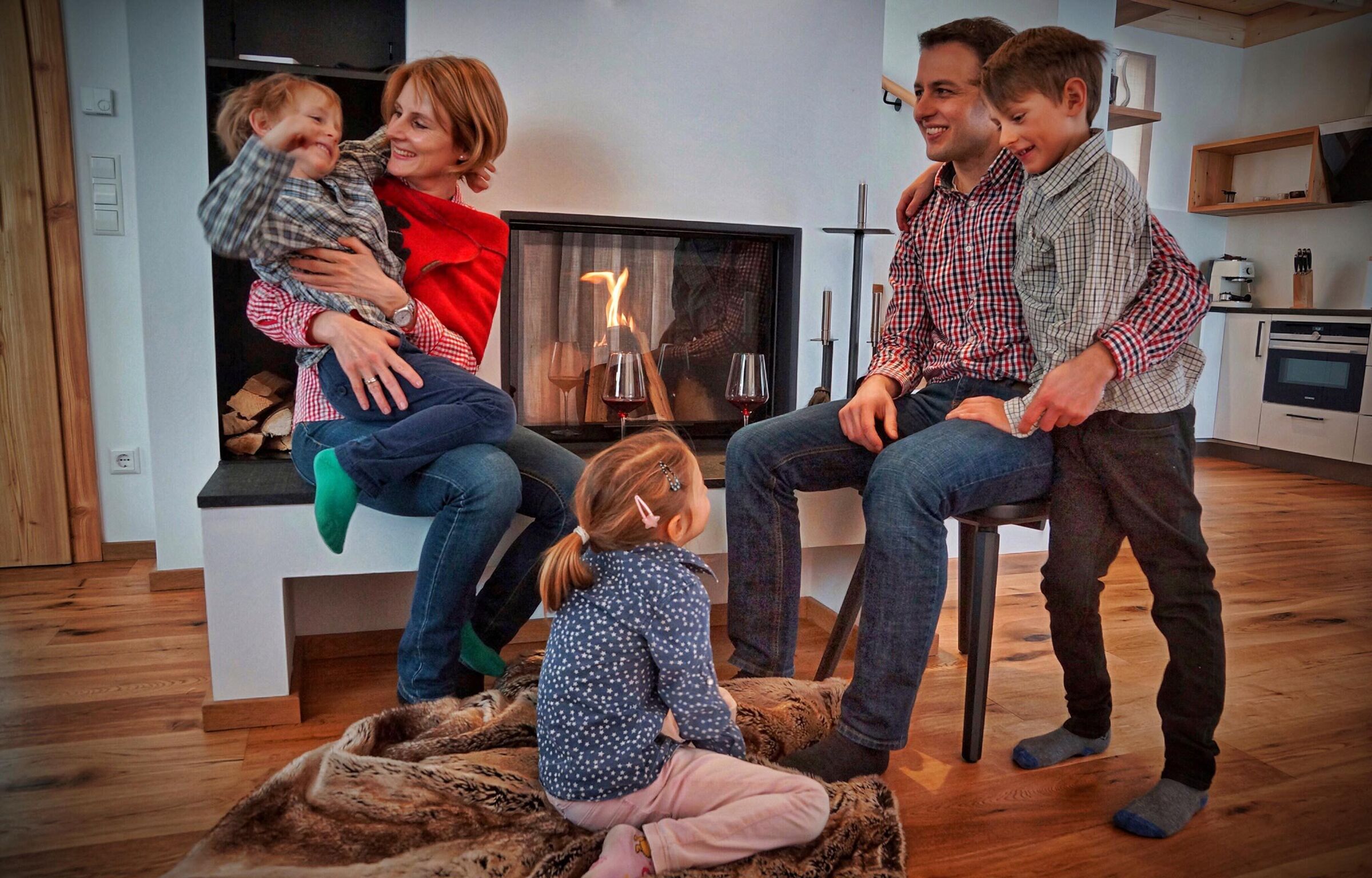 Familie genießt gemütliche Momente vor einem warmen Kamin in einem Chalet.