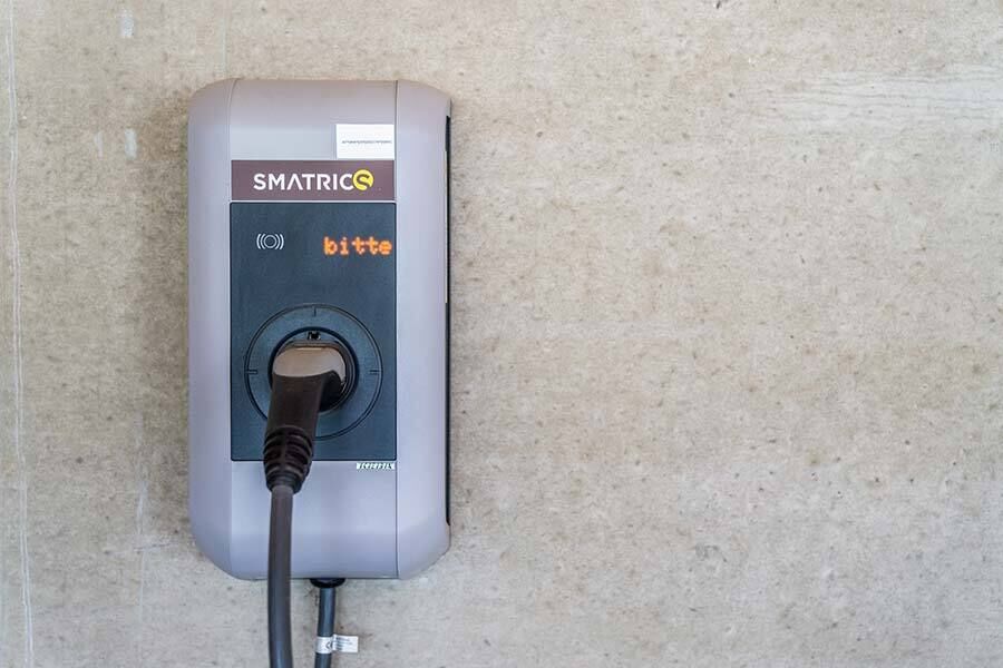 Stazione di ricarica Smatrics su muro di cemento per la ricarica ecologica dei veicoli elettrici.