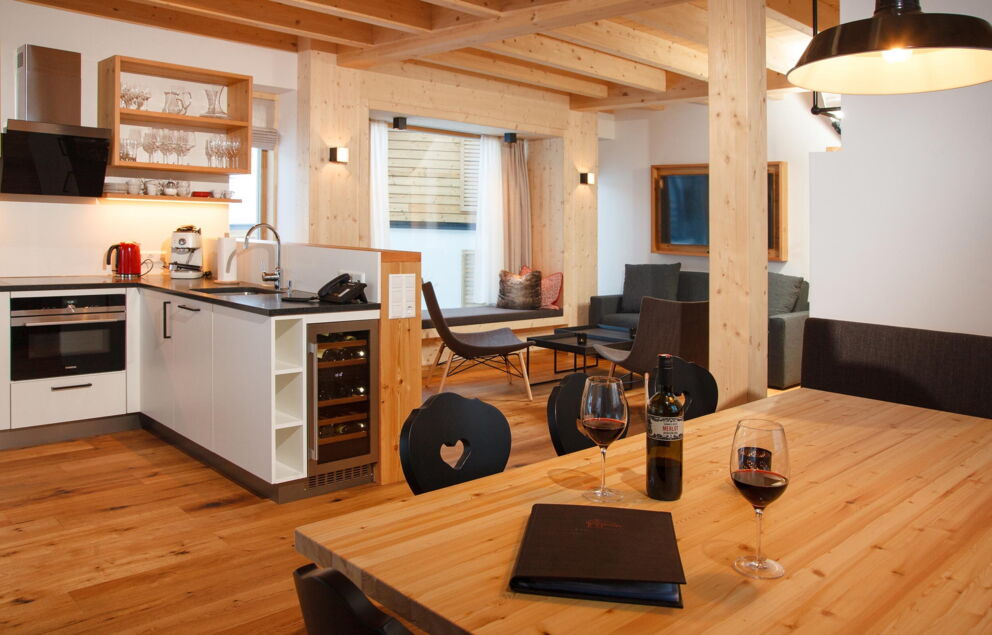Moderne Chalet-Küche mit Holzbalken, Weingläsern und gemütlichem Essbereich