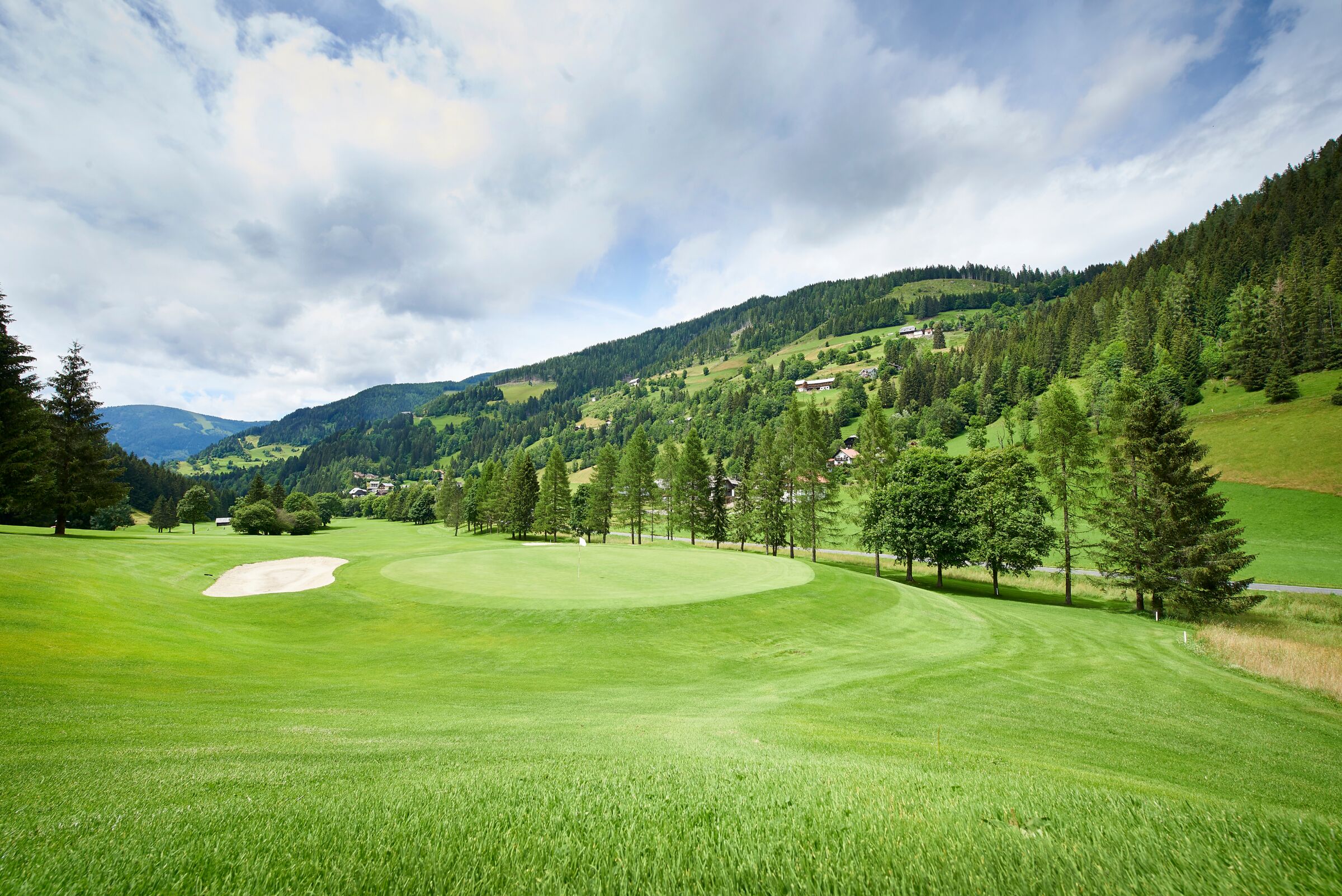 Extensive golf course in the middle of the green Carinthian Nockberge mountains surrounded by dense forests.