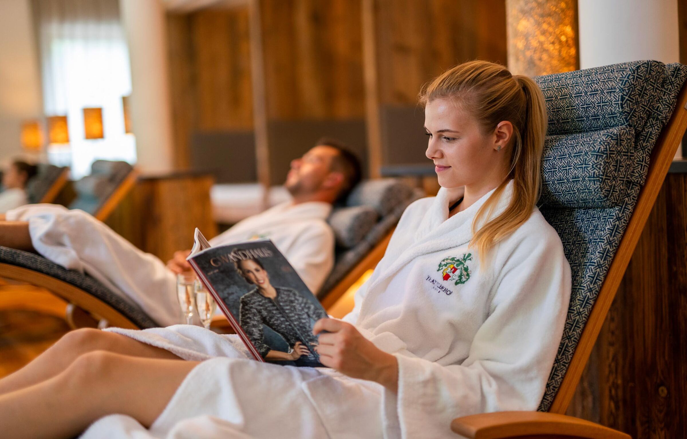 People relax in comfortable deckchairs with magazines in a wellness area.