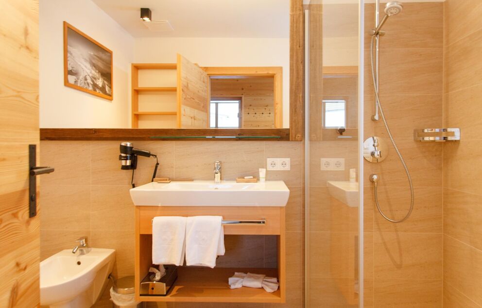 Stilvolles Badezimmer mit Duschkabine, Holzdetails und geräumigem Waschtisch.