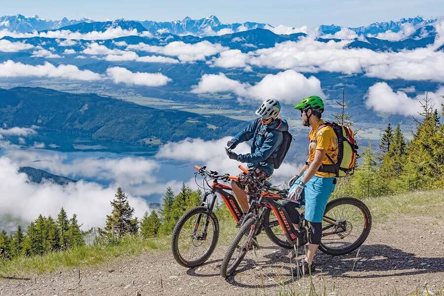 Zwei Mountainbiker genießen die spektakuläre Aussicht auf die Kärntner Berglandschaft.