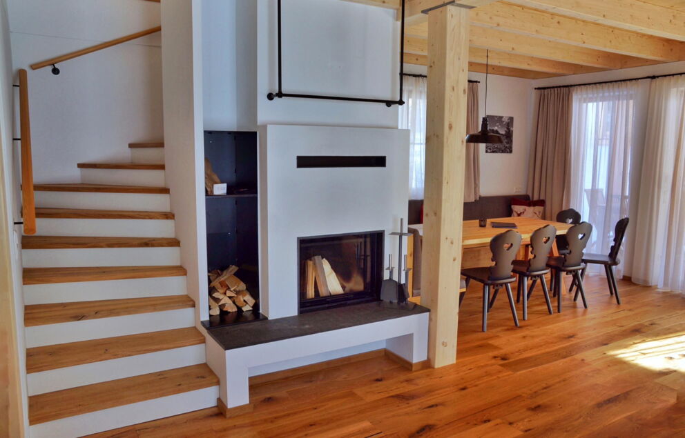 Heller Wohnbereich mit Holztreppe und Essecke in einem Chalet.