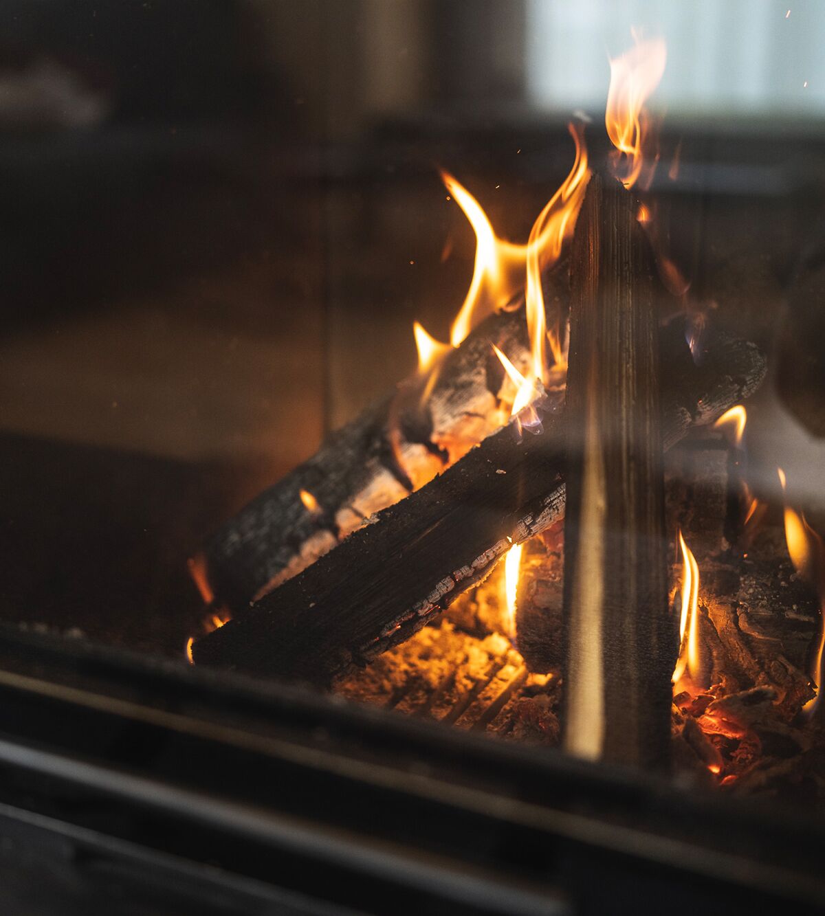Knistern des Feuers im gemütlichen Chalet-Kamin, Holzscheite brennen langsam.