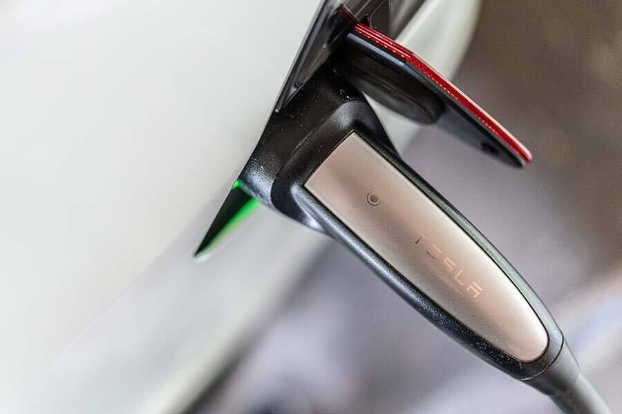 Elektroauto wird mit einem Schnelllader aufgeladen, grün leuchtende Anzeige sichtbar.