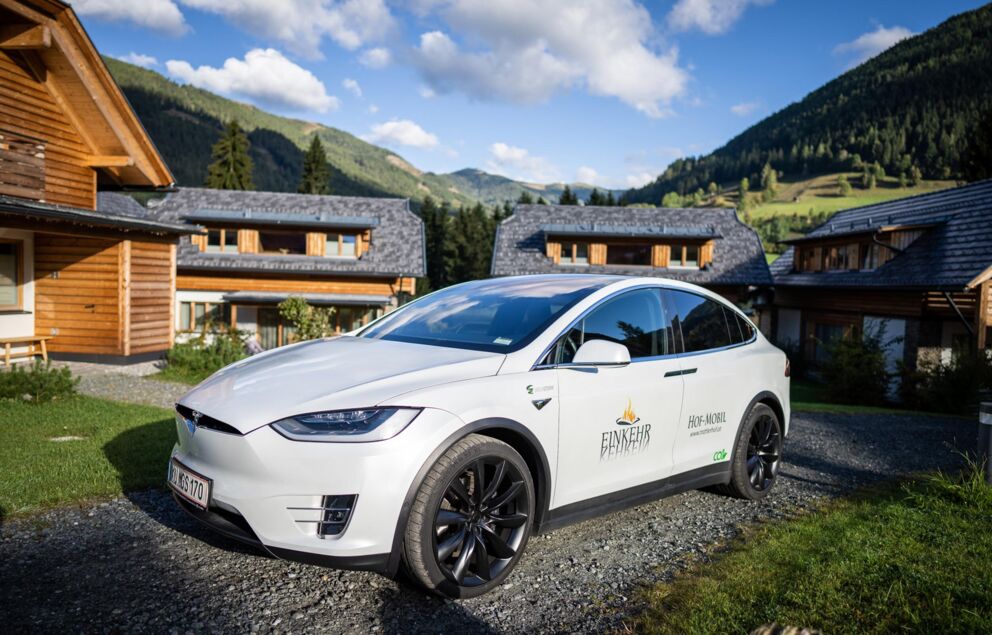Electric vehicle in front of luxurious chalets in a picturesque mountain landscape