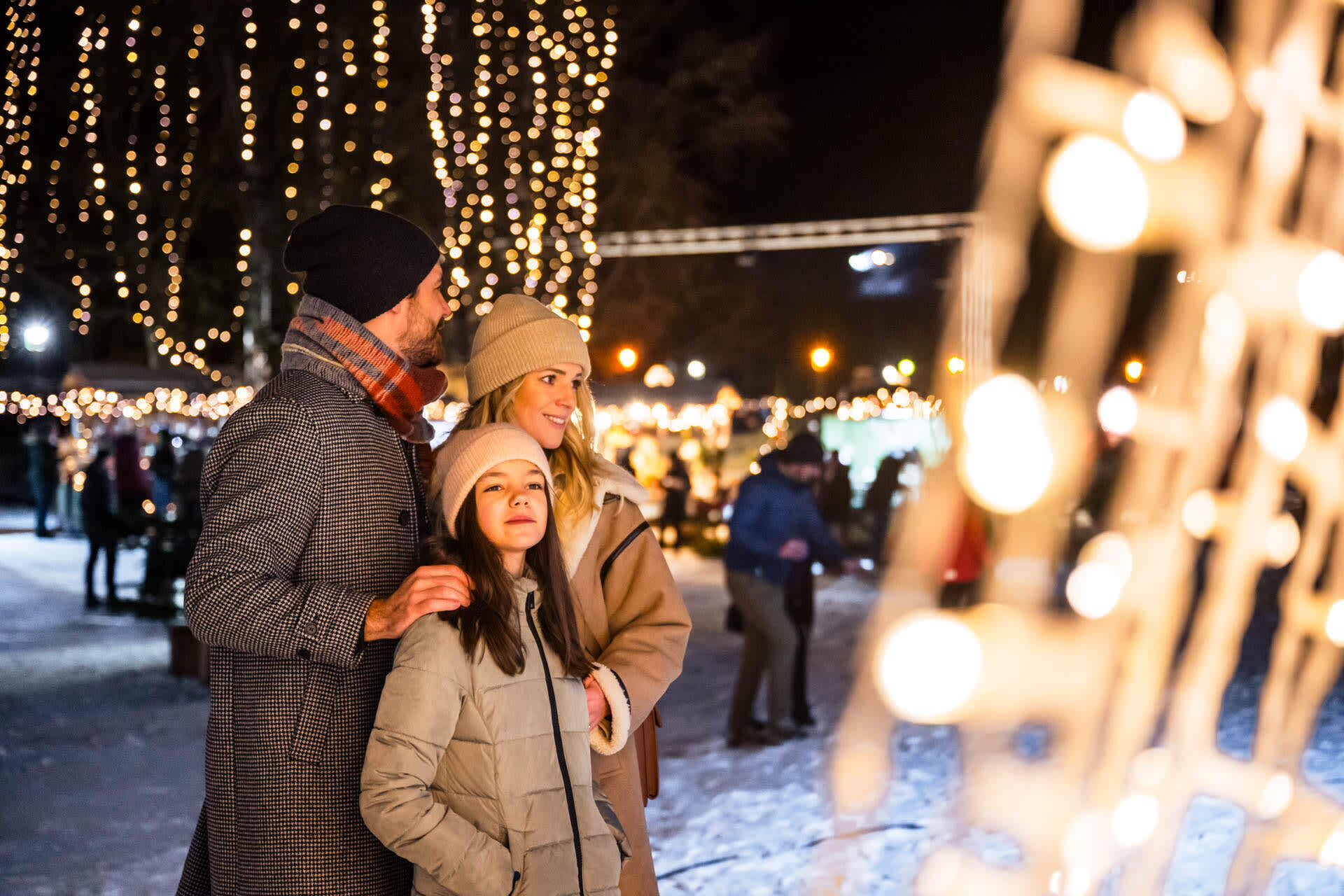 Familie genießt einen festlich beleuchteten Winterabend im Freien.