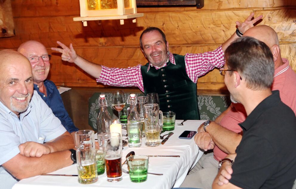 Gruppe fröhlicher Menschen genießt geselligen Abend in rustikalem Chalet-Restaurant.