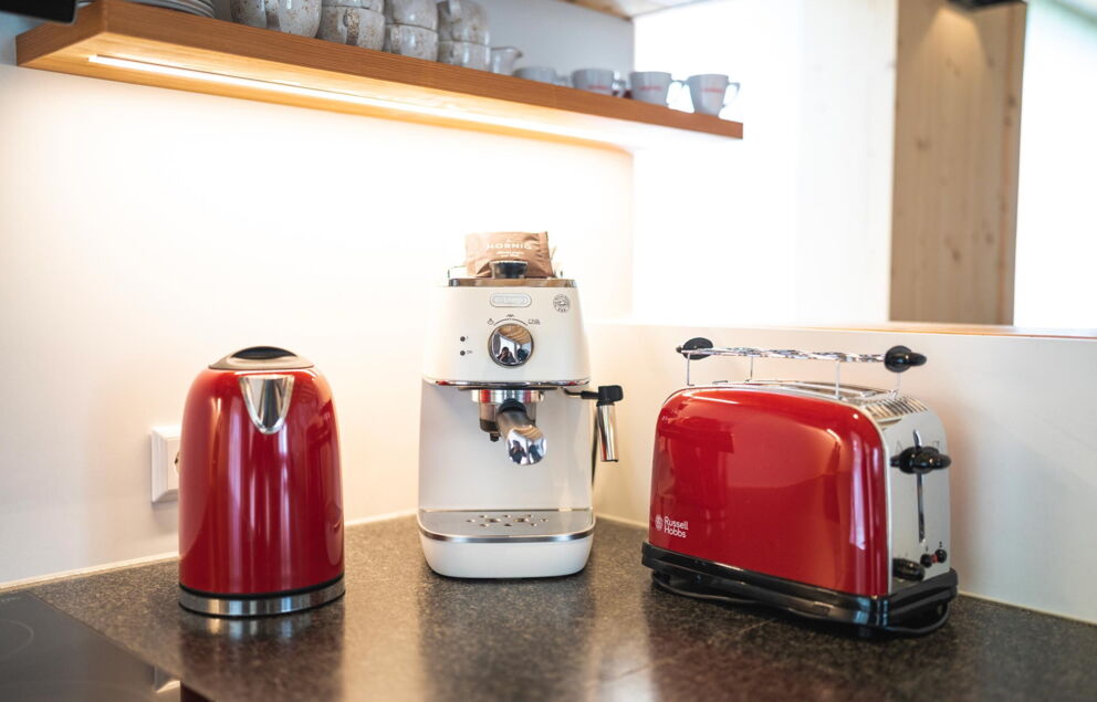 Rote Küchengeräte und weiße Kaffeemaschine auf einer modernen Arbeitsfläche in Chalet-Küche.