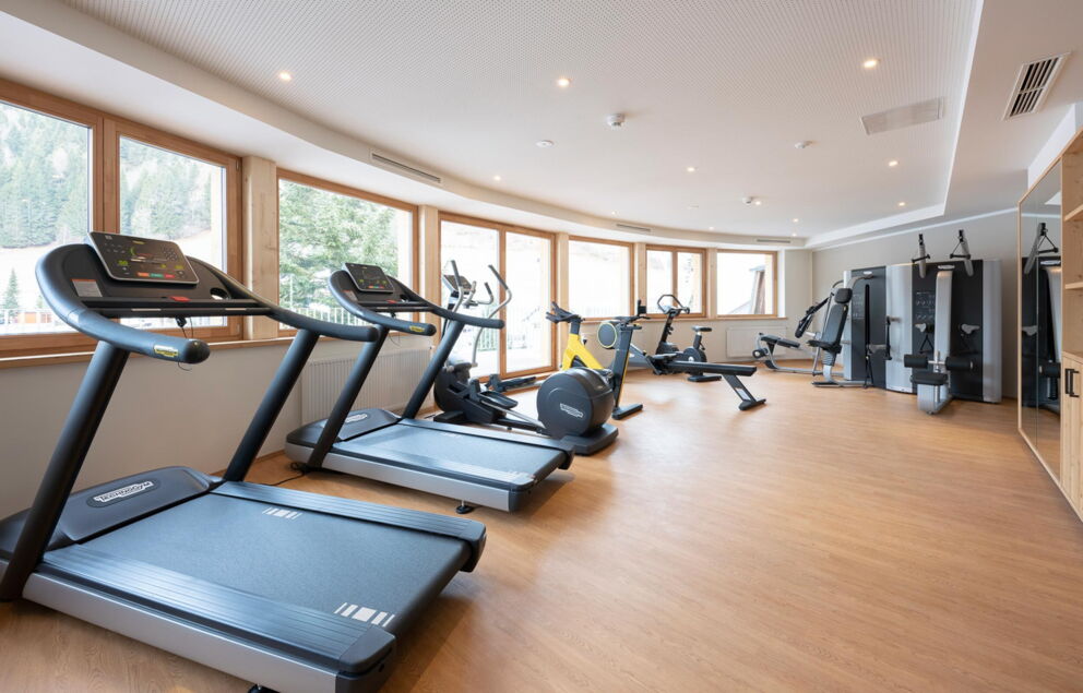 Modern fitness room with large windows and a view of the snow-covered mountains.