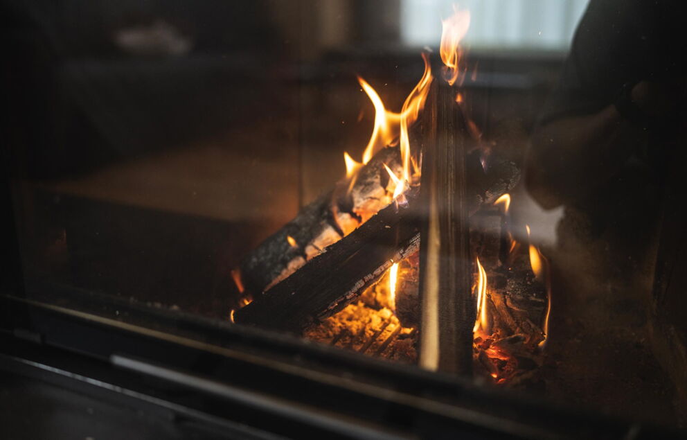Nahaufnahme eines behaglichen Kamins mit lebendigen Flammen und Holzscheiten.