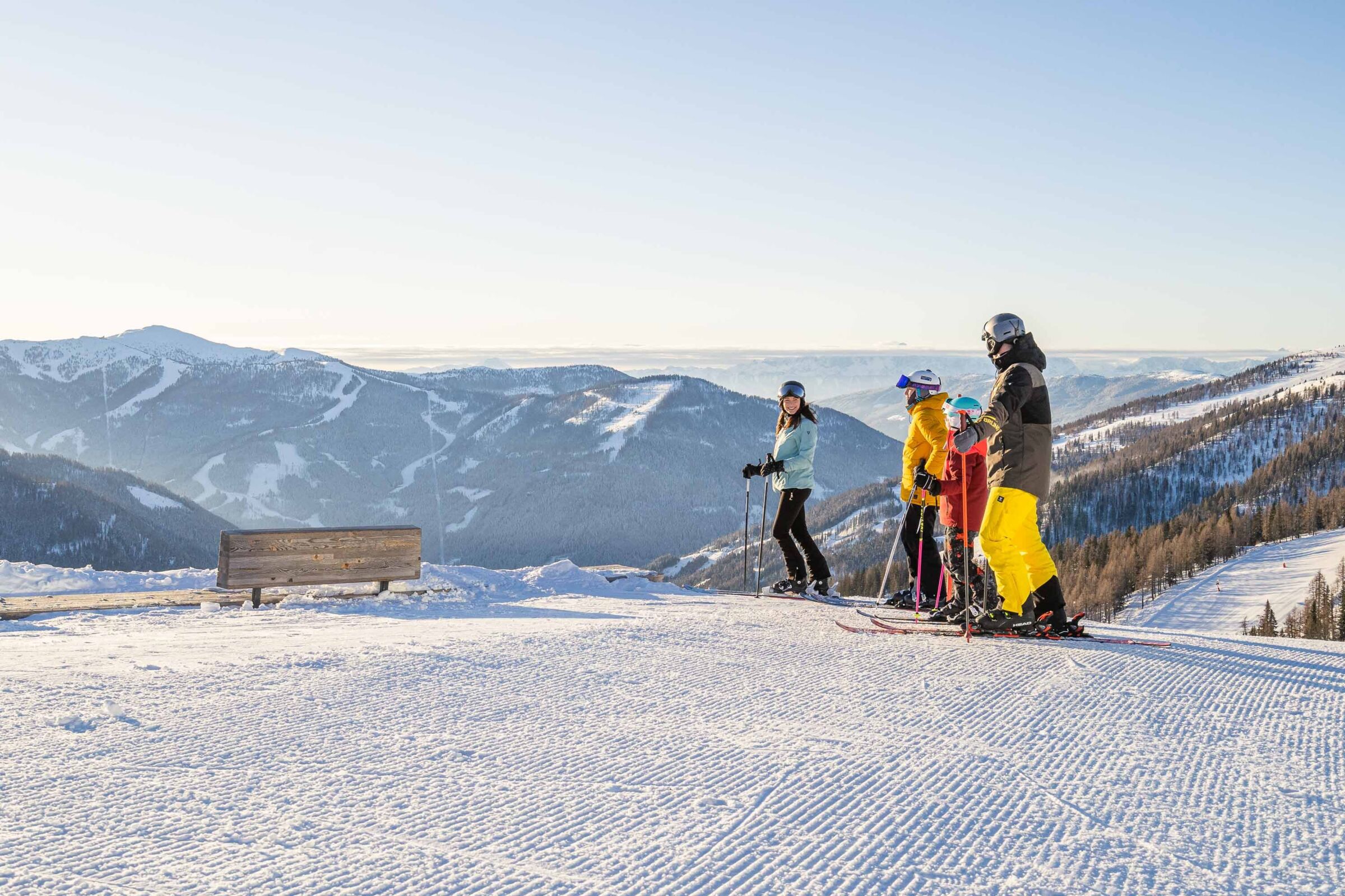 Family on skis enjoying the snow-covered mountains and clear skies.