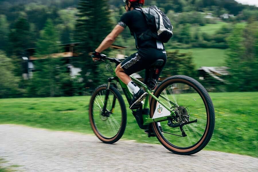 Person on a bicycle riding fast through a green landscape in the mountains.