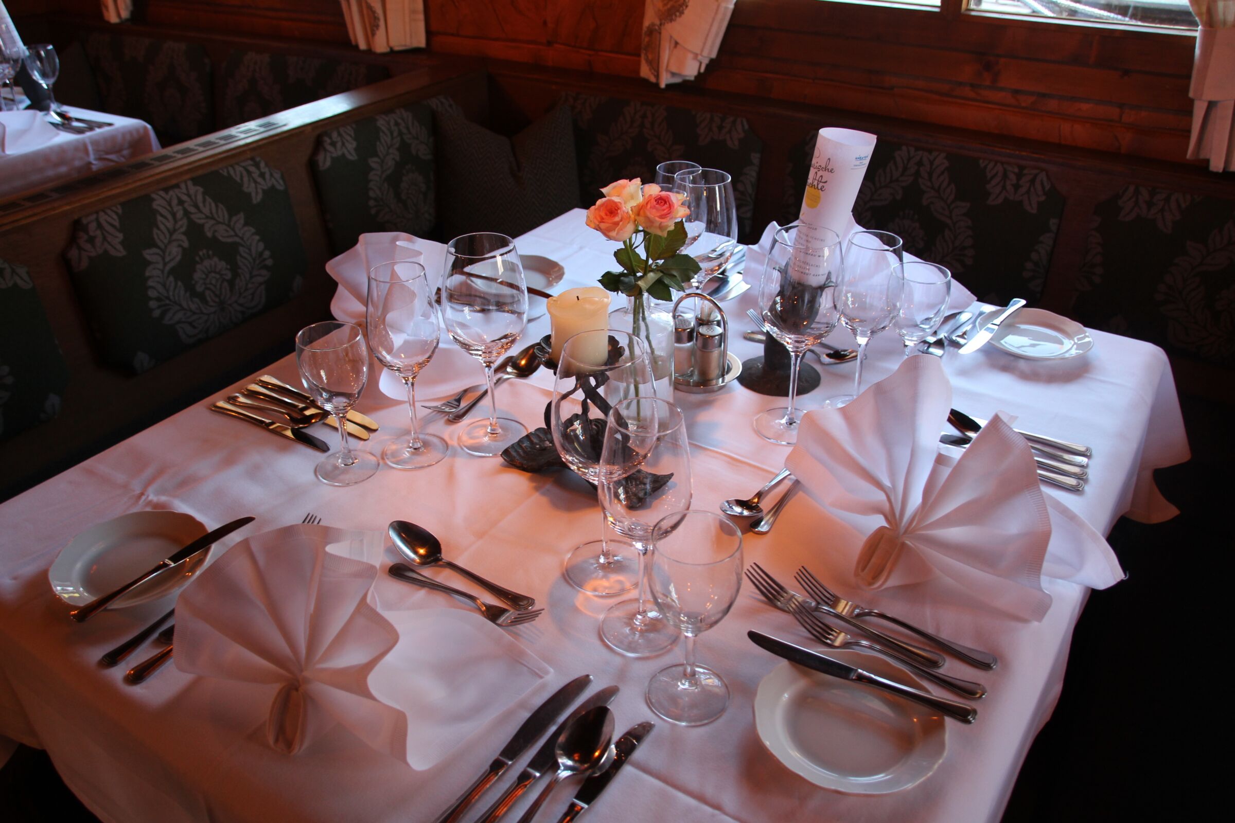 Elegant gedeckter Tisch mit feinem Besteck und frischen Blumen in gemütlicher Atmosphäre.