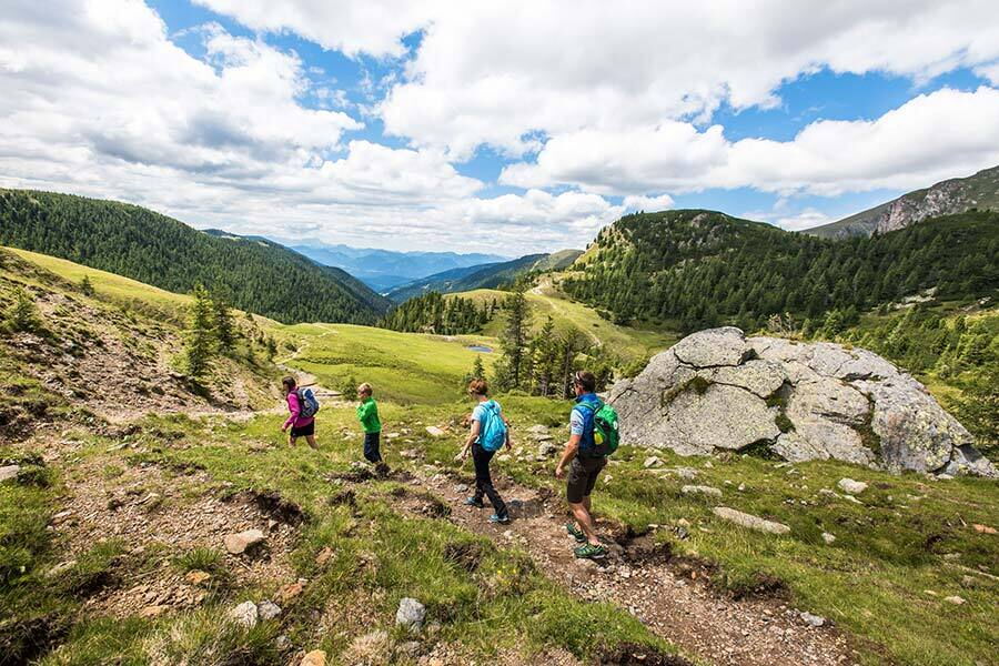 Familienwanderung in den grünen Hügeln der Nockberge unter blauem Himmel.