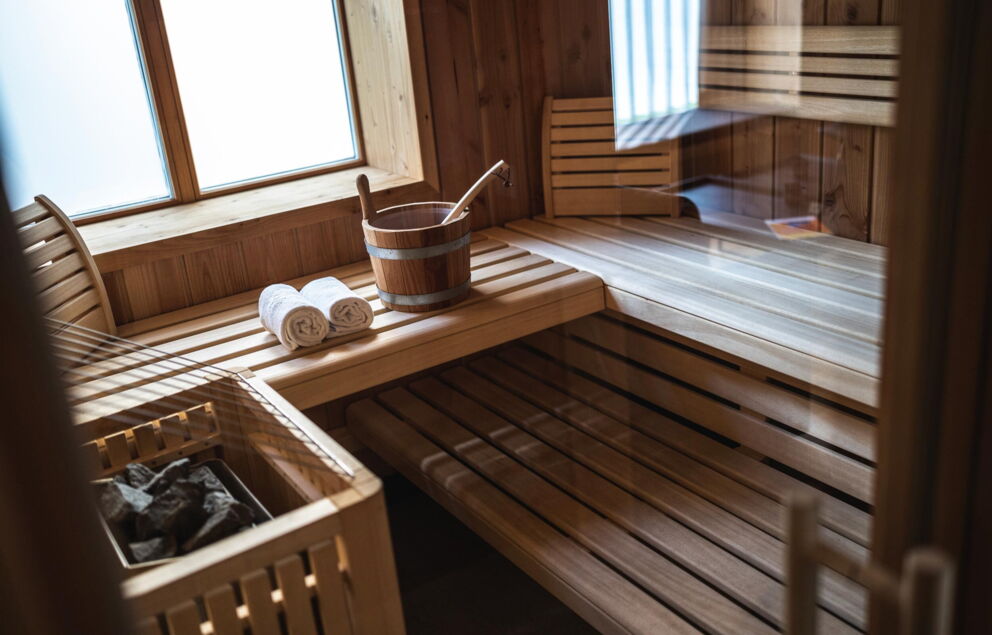 Sauna aus hellem Holz mit zwei Handtüchern und einem Wassereimer.