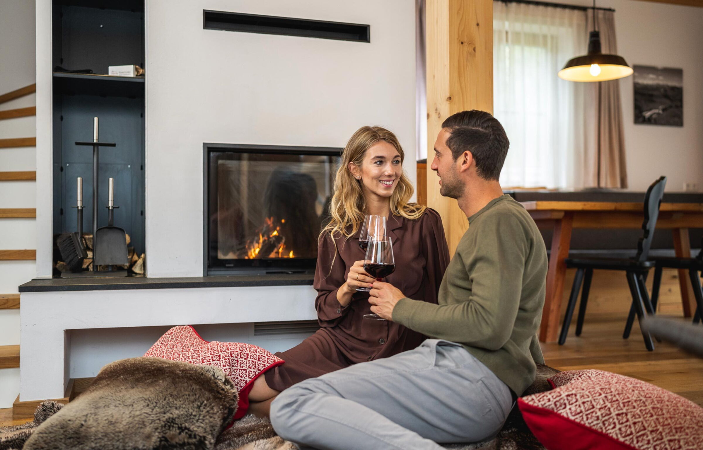 Paar genießt Wein vor einem gemütlichen Kamin im Chalet.