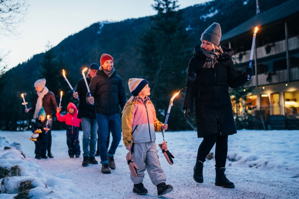 Eine Gruppe genießt eine Fackelwanderung im verschneiten Kärntner Winterwunderland.
