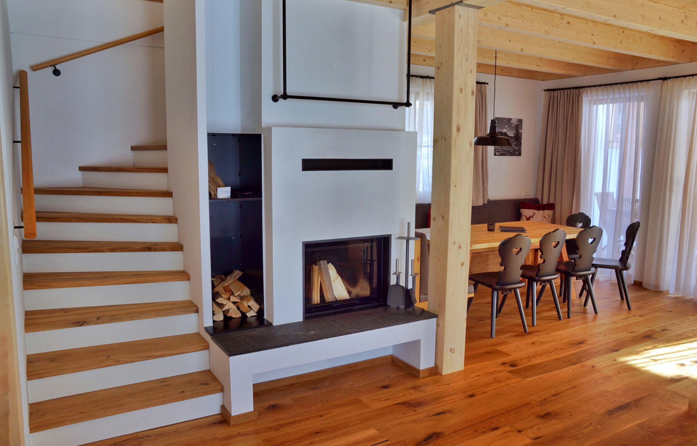 Bright living area with wooden staircase and dining area in a chalet.