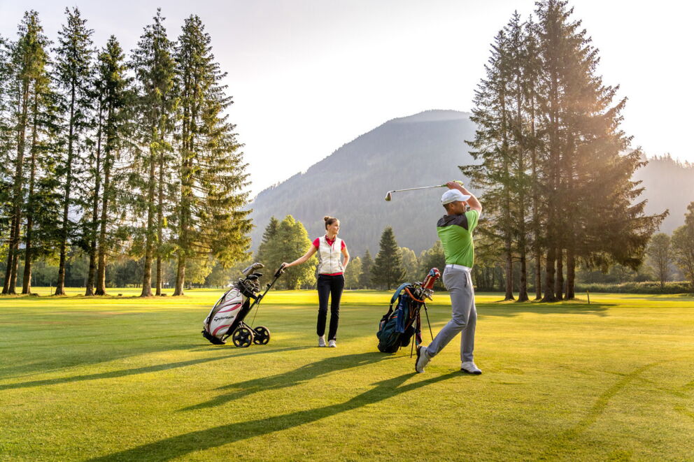 Zwei Personen beim Golfen auf einem sonnigen Platz in den Nockbergen.