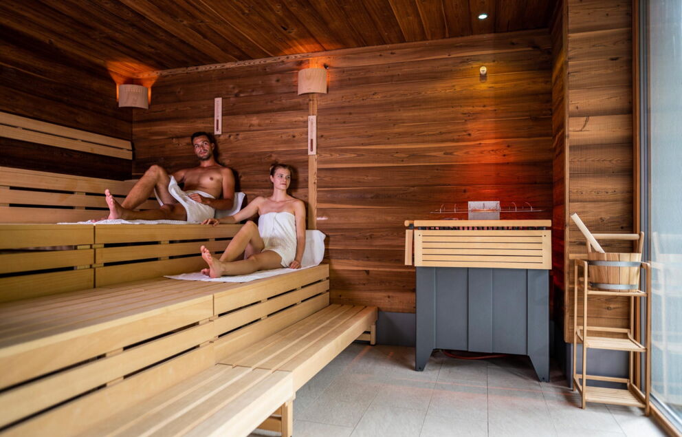 Couple enjoying relaxing moments in a sauna with wooden paneling.