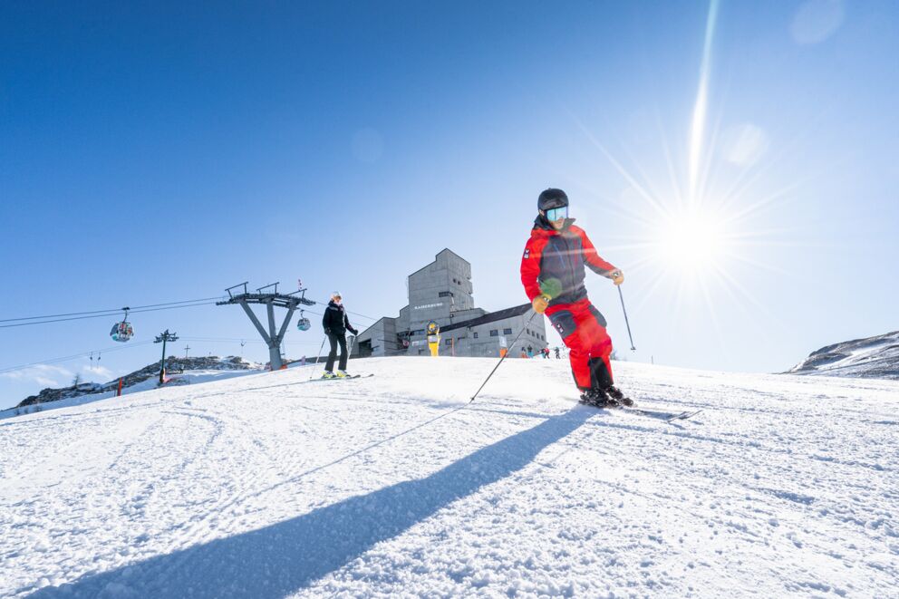 Sciatori vestiti di rosso al sole su una montagna innevata con un cielo blu.