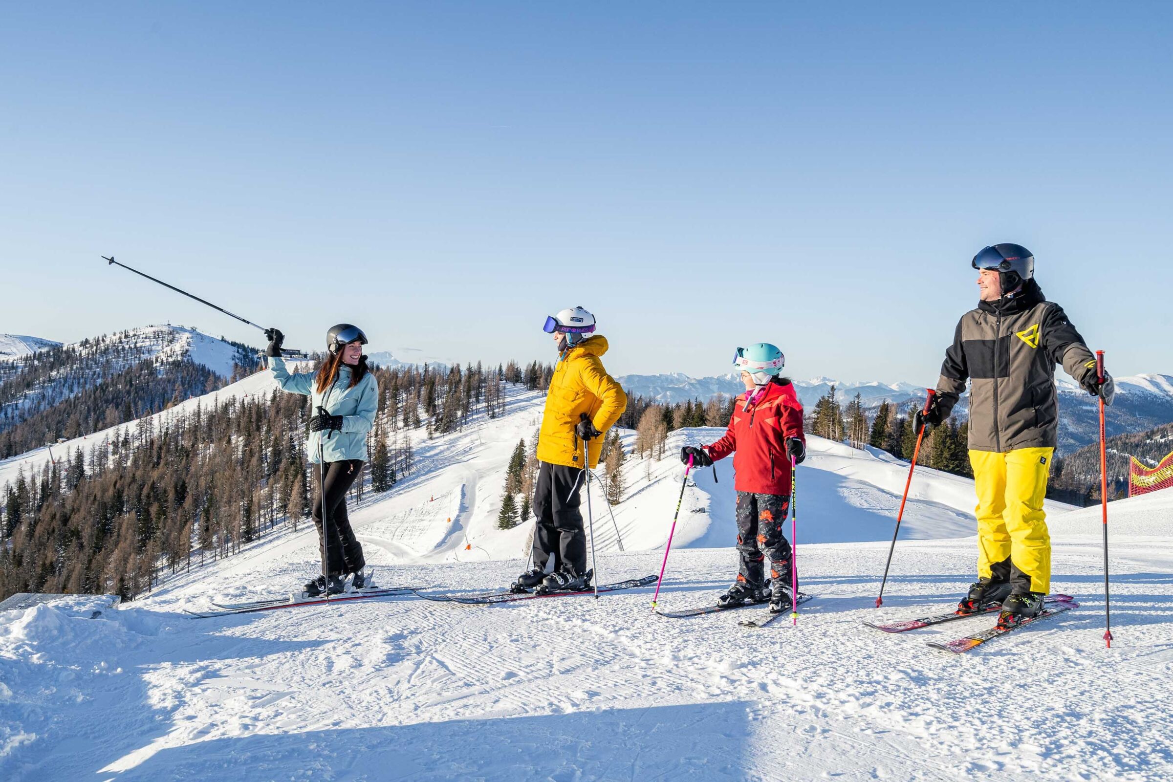 Skifahrer auf verschneiter Piste mit strahlendem Himmel und majestätischen Bergen.