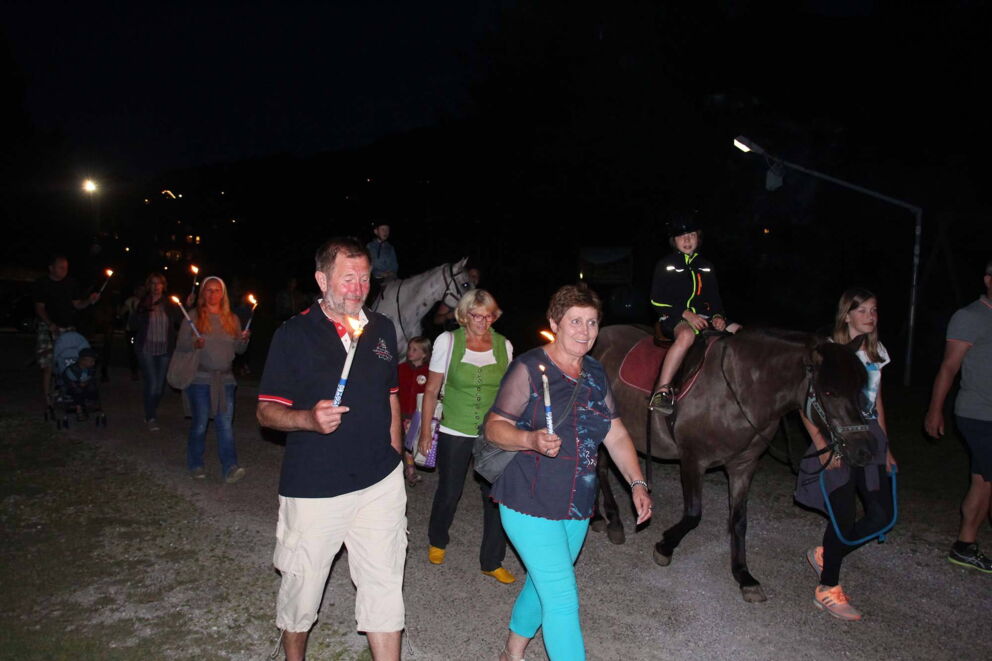 Gruppe bei nächtlichem Fackelritt mit Pferden und Kindern im Freien