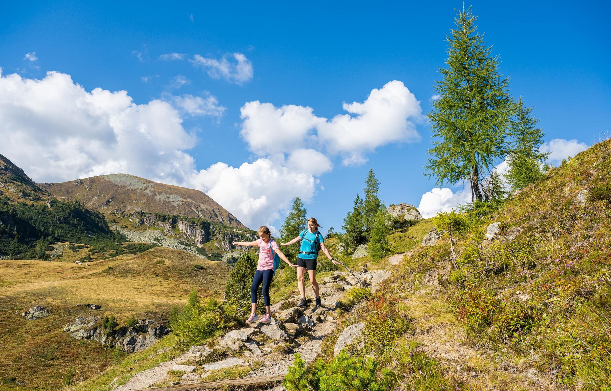 Zwei Frauen wandern bei sonnigem Wetter durch die malerischen Nockberge in Kärnten.