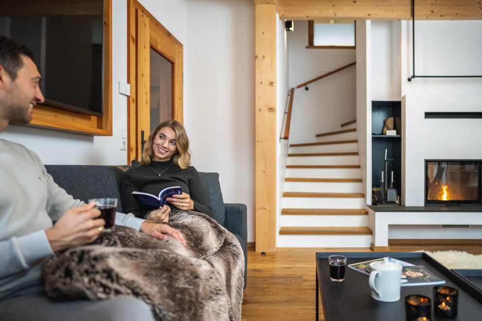 Couple enjoying a cozy evening in the chalet with fireplace and blanket.