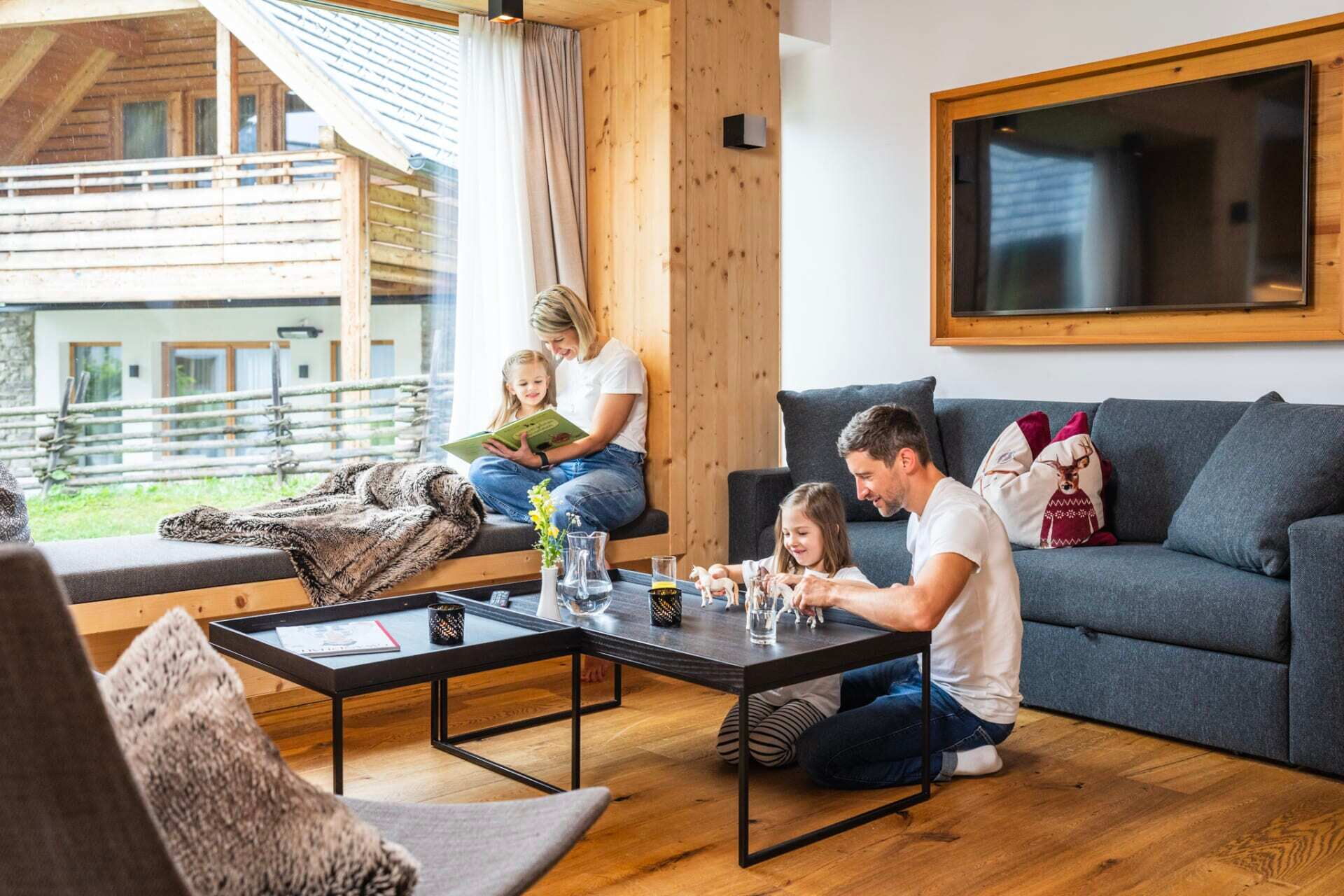 Familie genießt gemeinsame Momente im gemütlichen Chalet-Wohnzimmer mit Holzdetails.