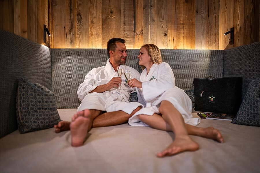 Coppia in accappatoio che beve champagne in un accogliente ambiente da chalet