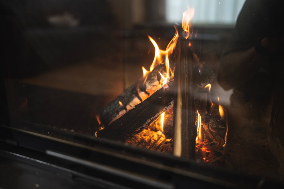 Nahaufnahme eines lodernden Feuers im Kamin mit glühenden Holzscheiten.