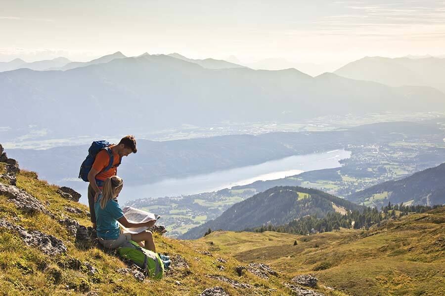 Due escursionisti godono di una vista mozzafiato sulle valli carinziane e sul lago scintillante.