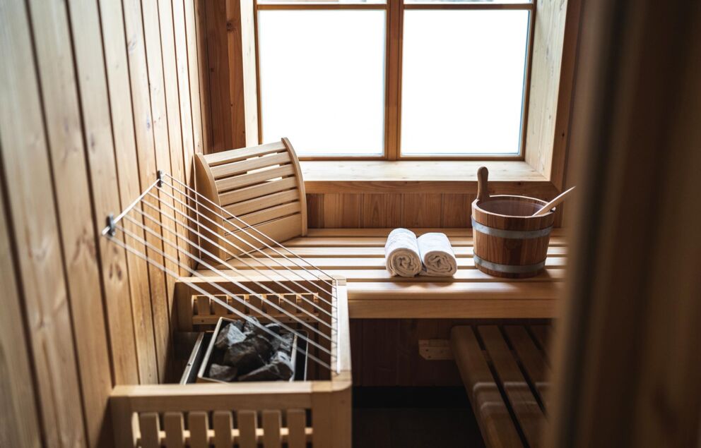 Sauna mit Holzverkleidung, Handtuchrollen und einem traditionellen Aufgusseimer.