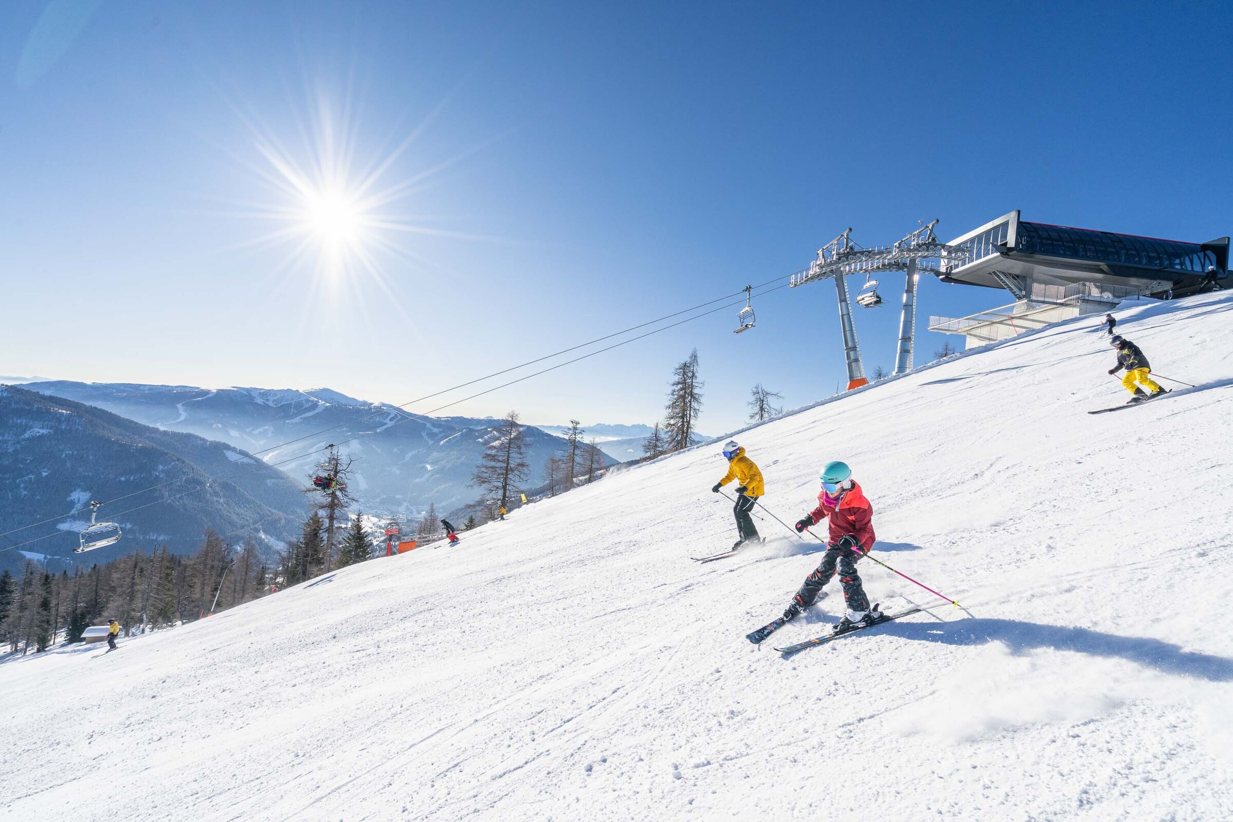 Skiers enjoy sunny slopes with a mountain panorama in Carinthia.
