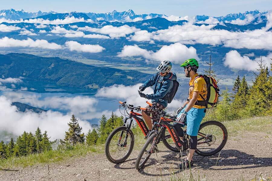 Zwei Mountainbiker genießen die spektakuläre Aussicht auf die Kärntner Berglandschaft.
