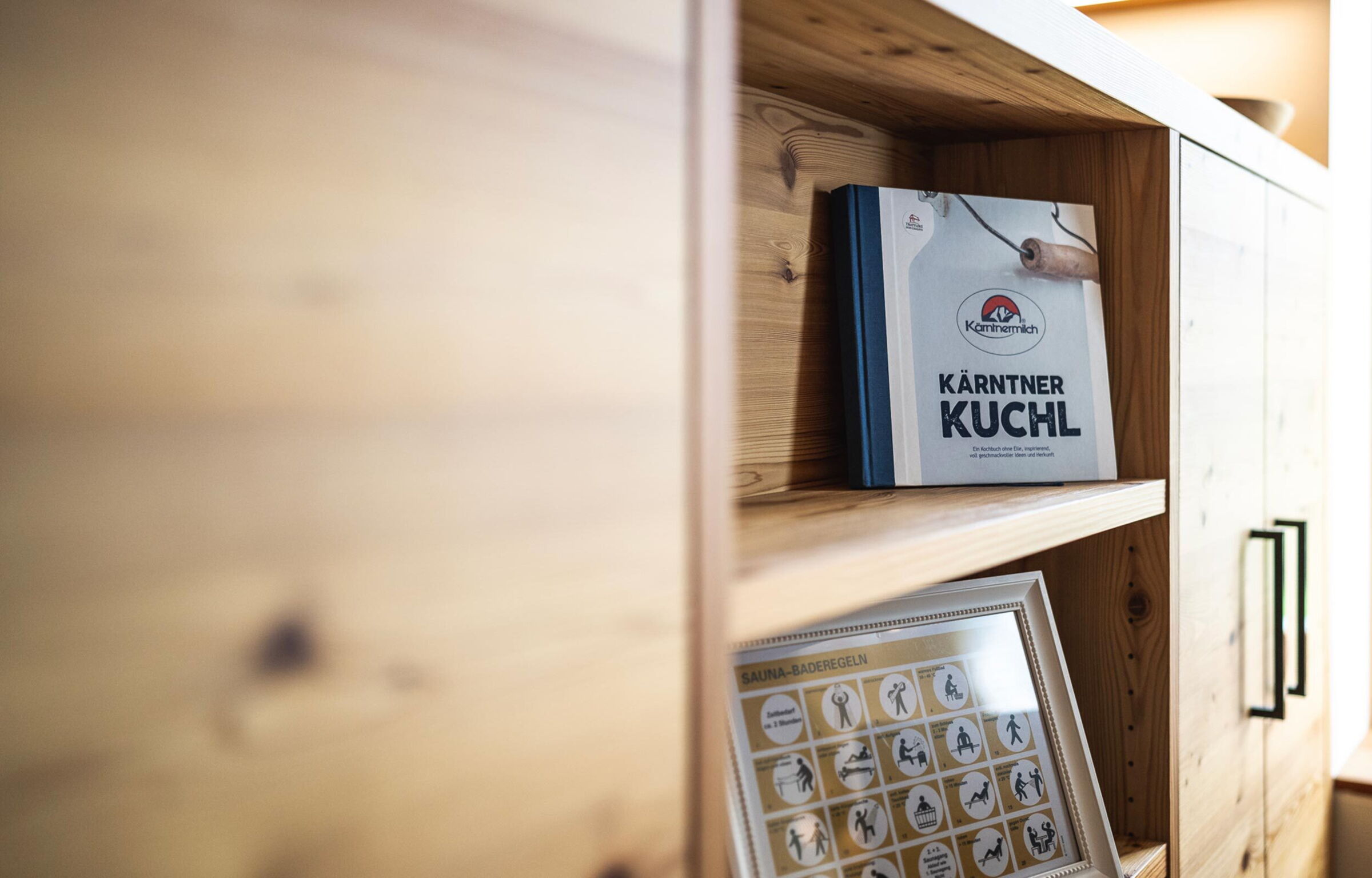 Cookbook and sauna rules on a wooden shelf for a cozy chalet atmosphere.