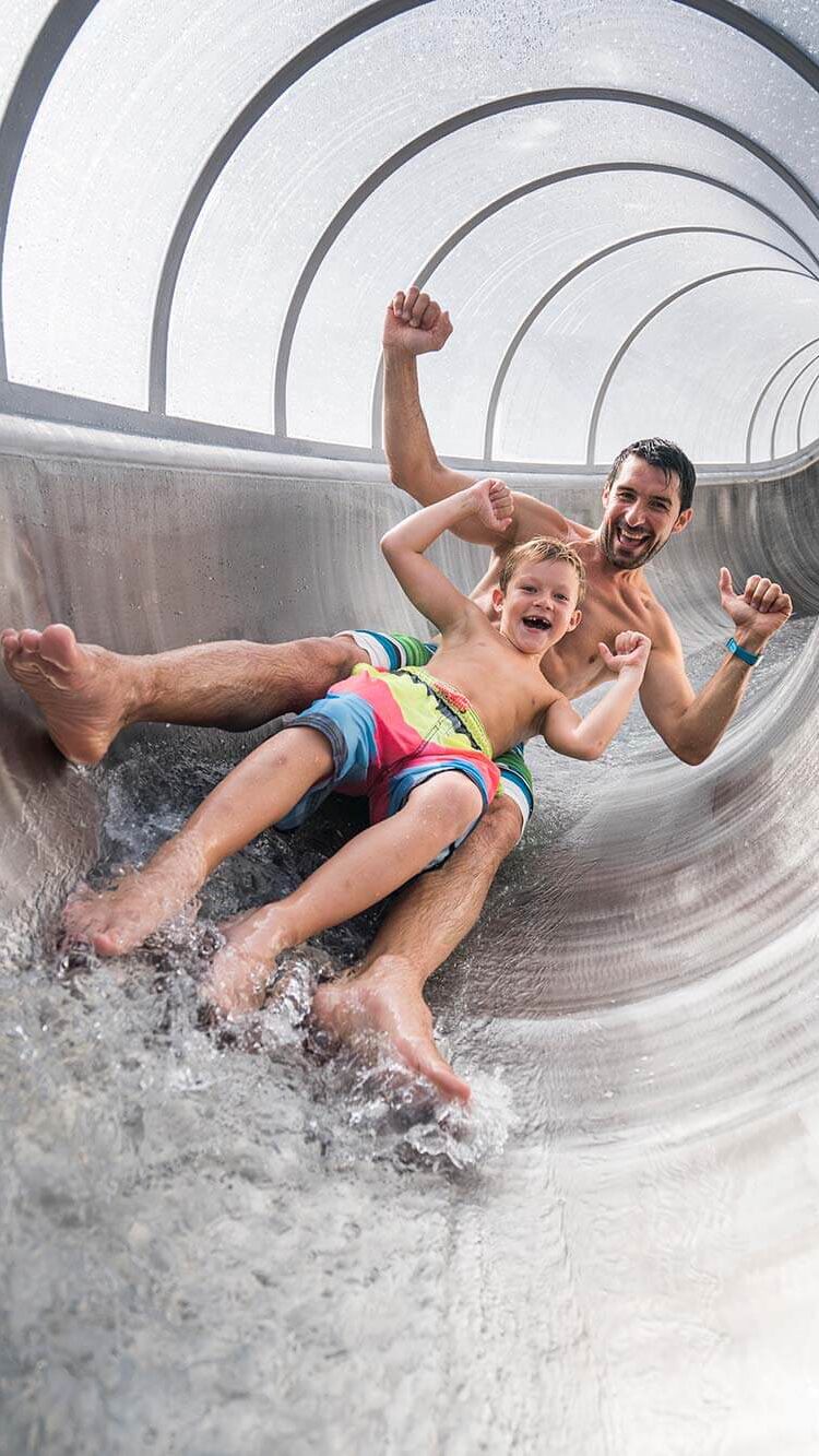 Father and son enjoy sliding down the water slide.