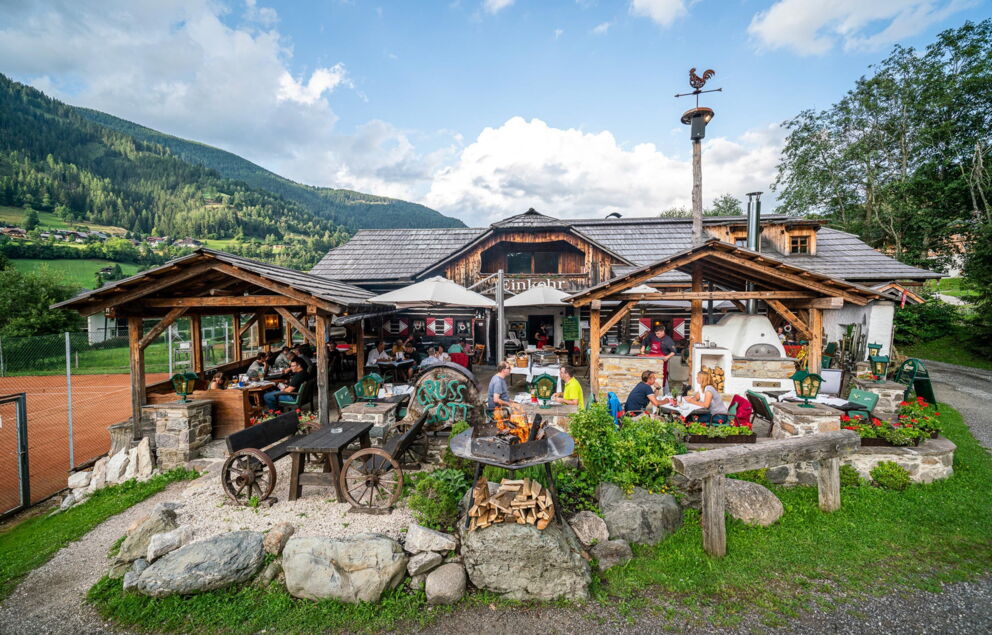 Gäste genießen die sonnige Terrasse des Einkehr Restaurants mit Bergblick.