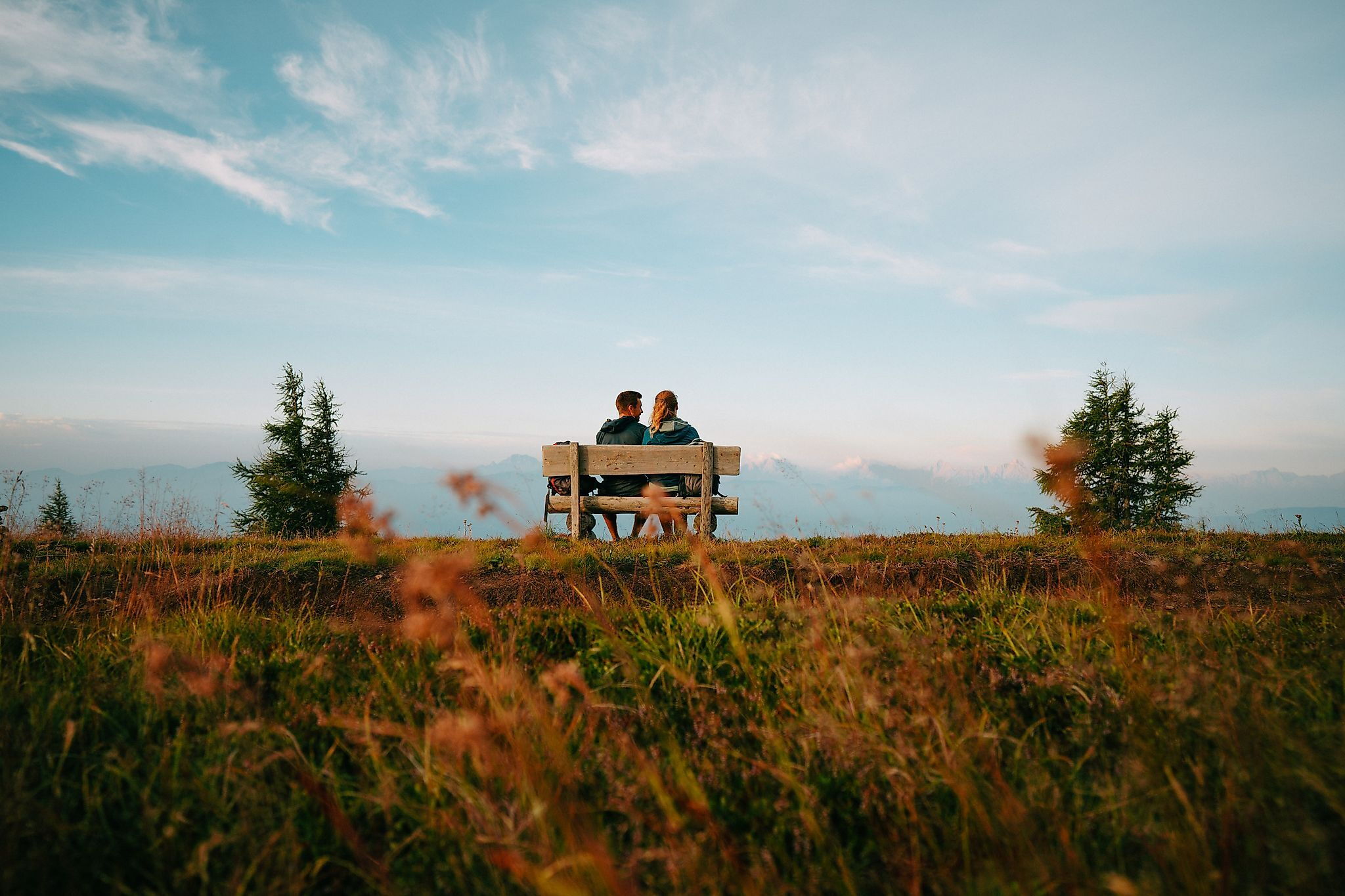 Couple sitting on a bench, enjoying the mountain view and peaceful natural scenery.