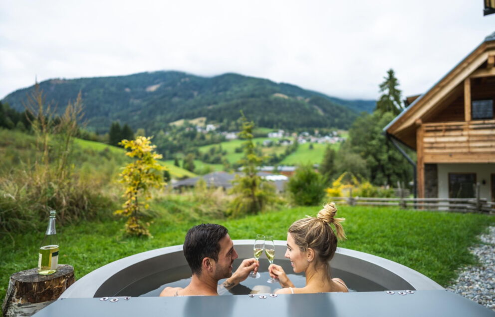 Paar genießt Entspannung im Outdoor-Whirlpool mit Blick auf die Nockberge.