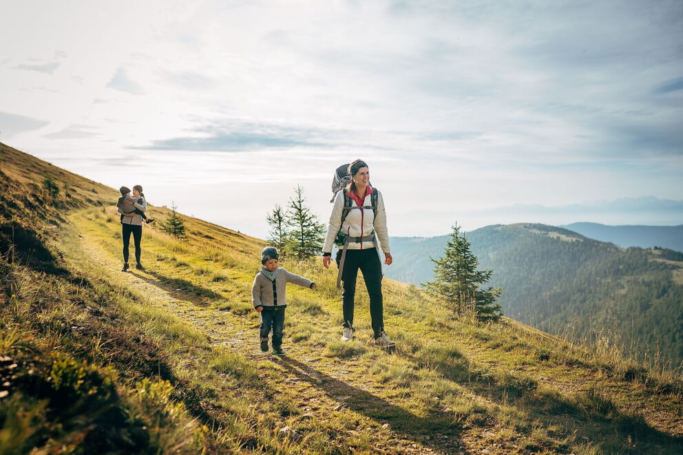 Familie wandert auf einem sonnigen Pfad in den Kärntner Nockbergen.