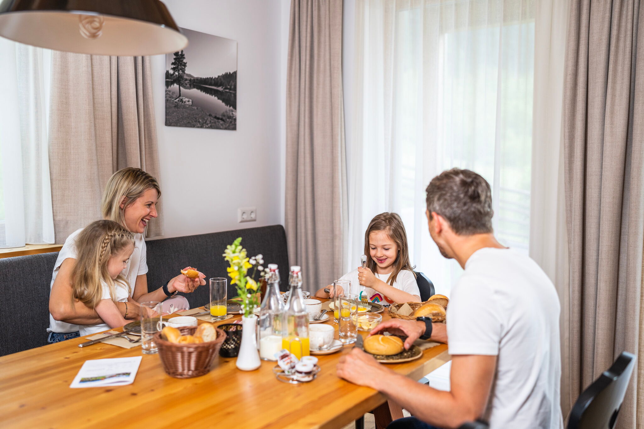 Family enjoying breakfast together with fresh rolls and orange juice in the chalet.