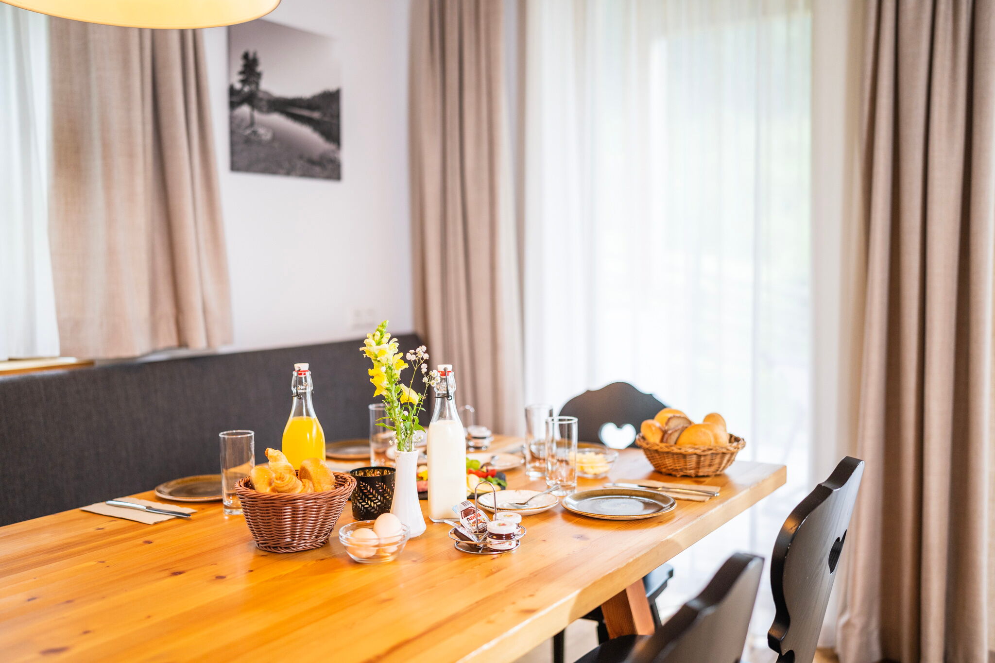 Tavola della colazione invitante con panini freschi, succhi di frutta e fiori in un accogliente chalet.