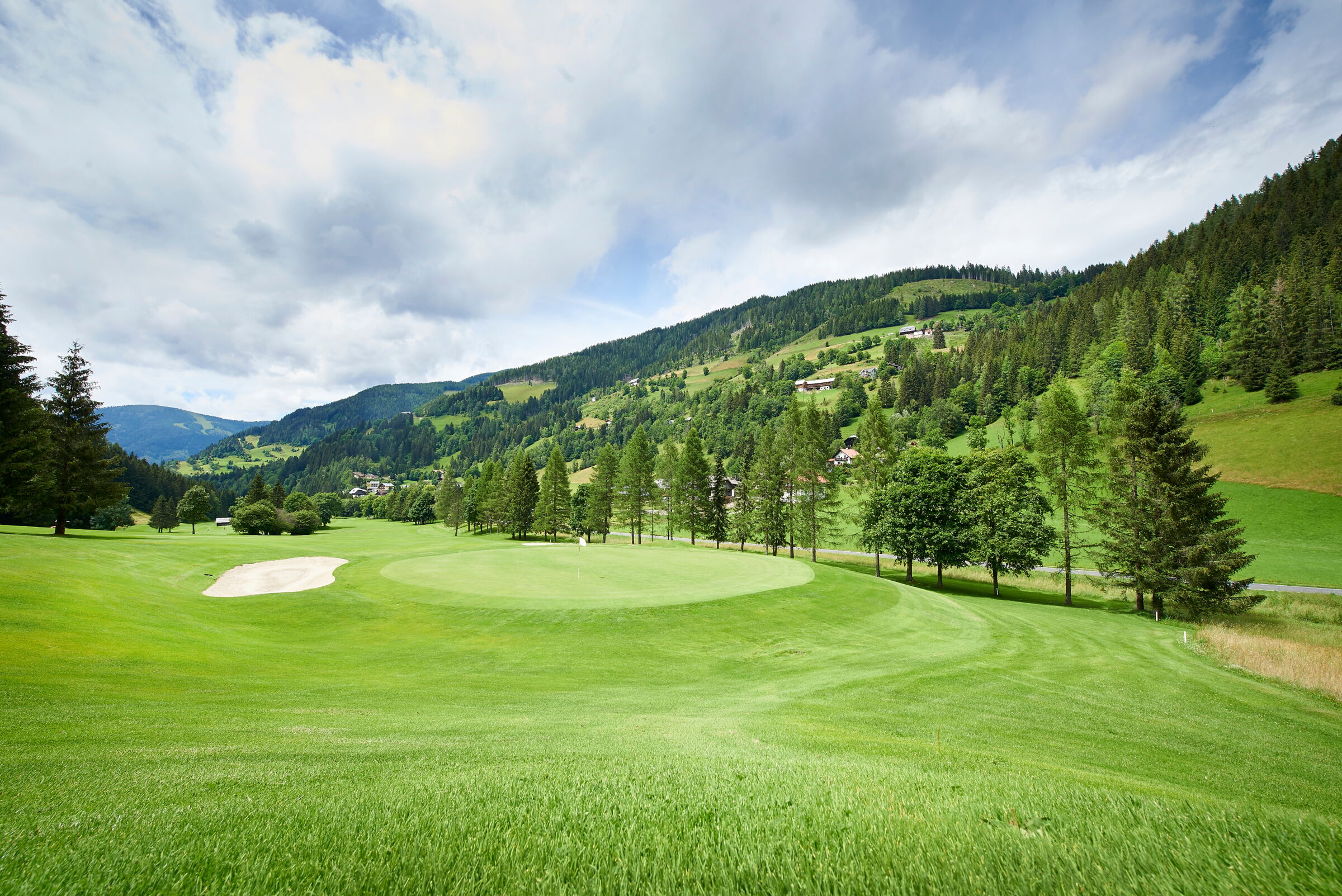 Weitläufiger Golfplatz inmitten der grünen Kärntner Nockberge umgeben von dichten Wäldern.