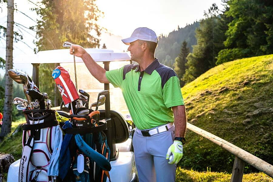 Golfer with equipment in the sunlight on a picturesque golf course.