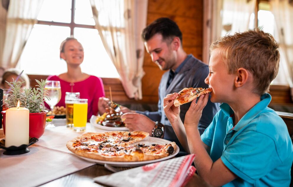 Fröhliche Familie genießt Pizza in gemütlichem Restaurantambiente.